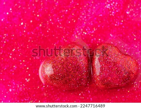 Two red heart filled with gel with glitter, concept of love, Valentine's Day, wedding. Sparkle bright heart on glitter and shine red background. 