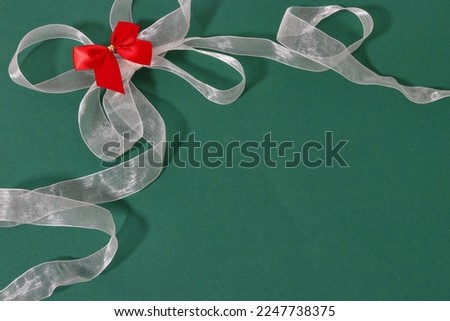white translucent ribbon with a red bow on a green background