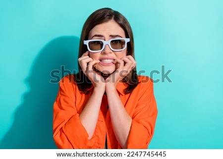 Photo of terrified worried nervous lady wear stylish clothes bite fingernails watching horror isolated on cyan color background