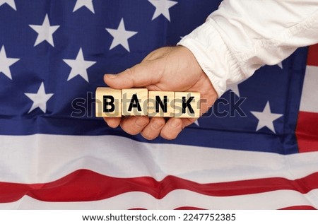 Business concept. Against the background of the USA flag, a man's hand with cubes with the text - BANK