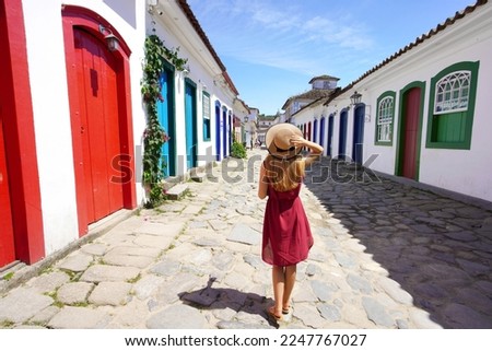 Holidays in Paraty, Brazil. Back view of beautiful fashion girl enjoying visiting historic town of Paraty, Rio de janeiro. Summer vacation in Brazil. Royalty-Free Stock Photo #2247767027