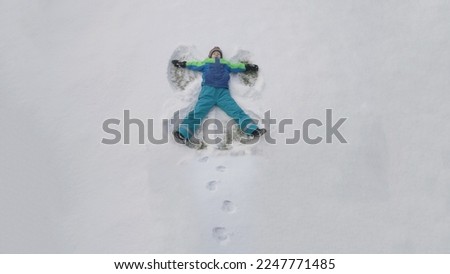 Little child make angels in snow, top view