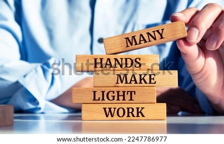Closeup on businessman holding a wooden block with "Many hands make light work" message