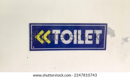 Voilet signboard affixed to the wall to show the direction of the toilet