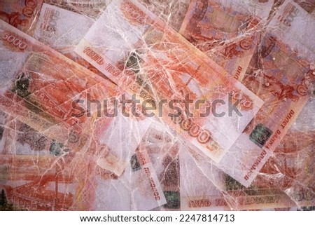 Blurred photo of  Five thousand rubles are thawed in ice. The Russian currency is frozen. Top view background.