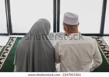 Back view of muslim couple reading Koran or Quran together at mosque Royalty-Free Stock Photo #2247815361
