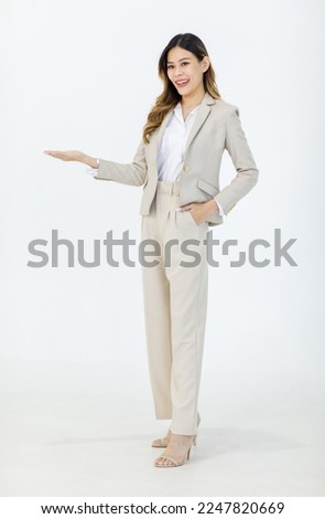 Portrait isolated cutout studio full body shot of Asian professional successful female businesswoman manager in formal suit standing smiling holding hand up presenting product on white background. Royalty-Free Stock Photo #2247820669