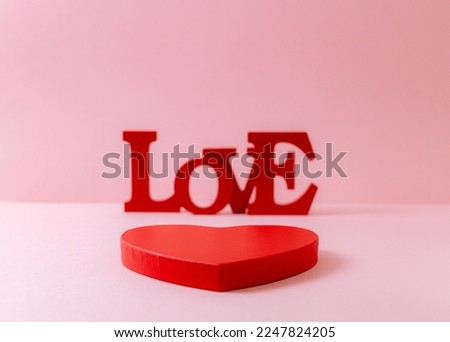 Red cardboard box and wooden solid word Love lie in the center on a pink blurred background, close-up side view. Valentine's day concept.