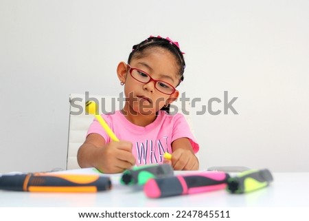 4-year-old brunette Latina girl with autism spectrum disorder ASD like Asperger, Rett and Heller draws at a desk, plays with colors alone antisocial Royalty-Free Stock Photo #2247845511