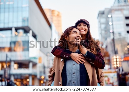 Young happy couple piggybacking and having fun together in the city. Royalty-Free Stock Photo #2247874597