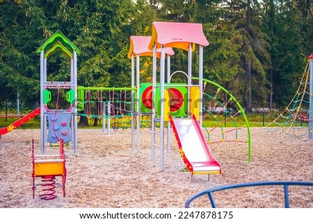 Colorful playground on yard in the park. Colorful children playground activities in public park surrounded by green trees
