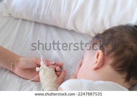 sick toddler in hospital holding mother's hand while sleeping Royalty-Free Stock Photo #2247887531
