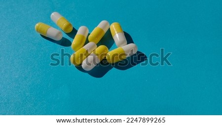 medicine in the form of yellow and white capsules on a blue background