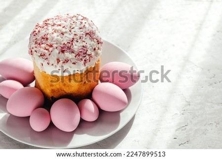 Easter cake garnished with sugar on a gray background. Pink-dyed Easter eggs.