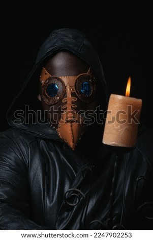 Plague doctor with crow-like mask and candle isolated on black background Creepy halloween historical terrible costume concept Epidemic covid smallpox monkeypox