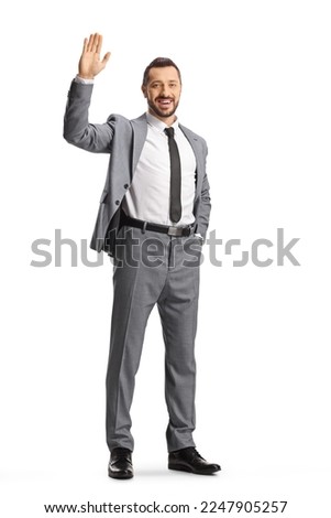 Professional man in a suit smiling and waving at camera isolated on white background Royalty-Free Stock Photo #2247905257