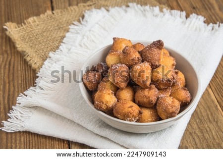 Homemade Castagnole, typical italian carnival fritters with sugar in a white bowl on rustic wooden table Royalty-Free Stock Photo #2247909143