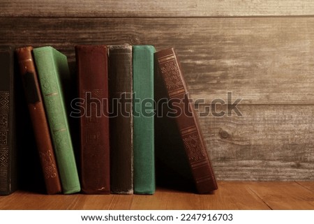 Different old hardcover books on wooden table, space for text