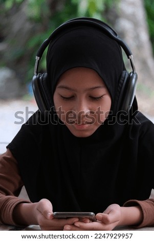 Happiness Malaysian smiling young woman wearing technology wireless headphones for listening to the music via smart mobile phone