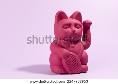 a Maneki-neko plastic cat, Symbolizing luck and wealth, on a pop and colorful background. Minimal color still life photography Royalty-Free Stock Photo #2247938953