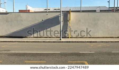 Pole on the sidewalk with bus stop sign and concrete wall behind. urban road in front. Background for copy space.