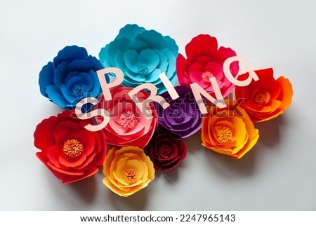 Handmade paper art colorful flowers on blue background. With spring lettering. 