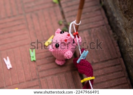 a knitted pink pig hangs things on clothespins