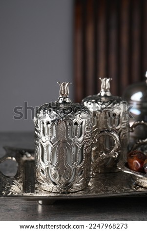 Tea and date fruits served in vintage tea set on grey textured table, closeup