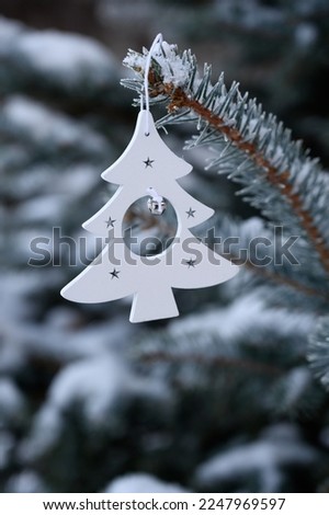 White toy in the form of a Christmas tree on a snowy Christmas tree. Winter
