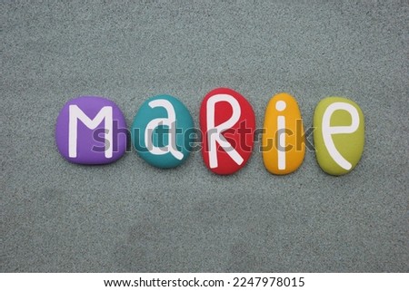 Marie, female given name composed with multi colored stone letters over green sand Royalty-Free Stock Photo #2247978015