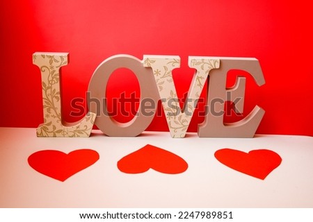 Word LOVE with three hearts en white and red background