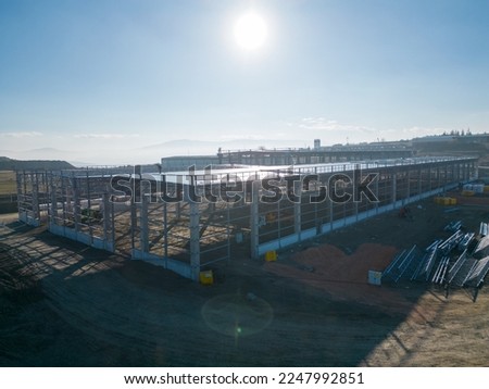 Photograph of the new warehouse under construction, taken from a height with a drone, in reverse light.