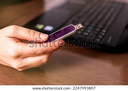 Close-up view of a woman's hand with an external memory stick near the notebook Royalty-Free Stock Photo #2247993807
