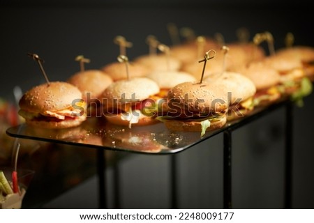 Juicy burgers on a stand. Catering. Lots of cheeseburgers. Fast food. street food 
