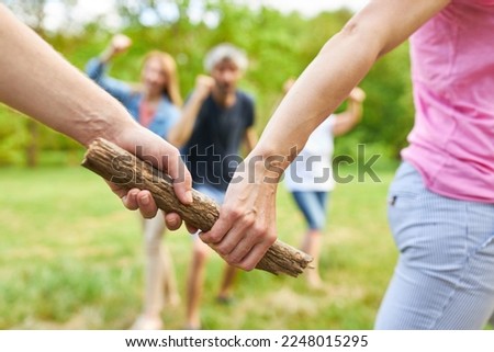 Handing over of the wooden baton in the race with a cheering team in the background Royalty-Free Stock Photo #2248015295