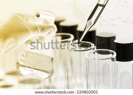 gloved hand hold a flask in laboratory room