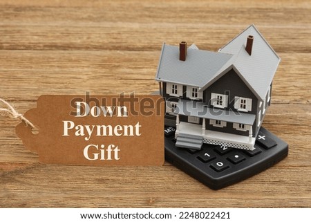 Down Payment Gift rules with a mortgage calculator and gift tag with a house on a wood desk