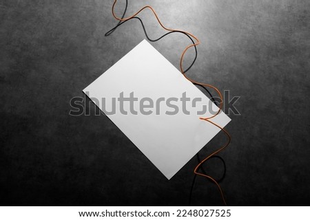 Branding poster, A format letter mockup template on a dark concrete background with orange wire and deep shadows, real photo. Blank isolated to place your design. 