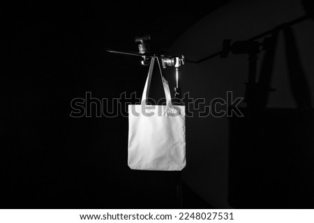 Tote Bag branding mockup template on a metal tripod with deep shadows, real photo. Blank isolated to place your design. 