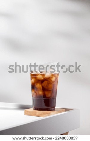 Iced americano in a plastic mug on a white table in the cafe.	 Royalty-Free Stock Photo #2248030859