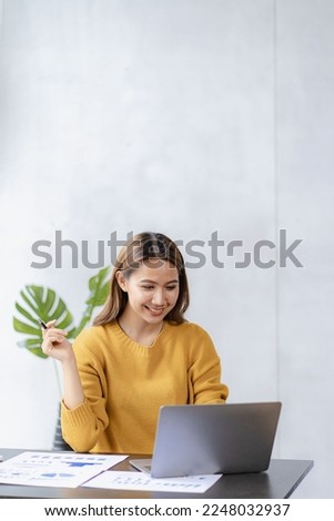 Young Asian freelancer doing her work on laptop computer in modern home Make a real estate investment data account analysis report vertical image