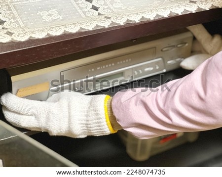 Gloved hand holding an old DVD player Royalty-Free Stock Photo #2248074735