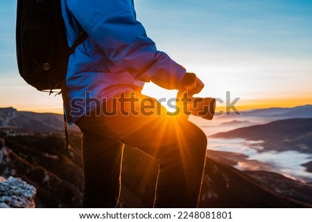 A male photographer relaxing on the mountain top during the hiking at sunrise or sunset adventure travel.	