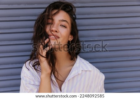 Beautiful young caucasian girl tender posing looking at camera with gray background. Brunette wears white shirt. Leisure concept. Royalty-Free Stock Photo #2248092585