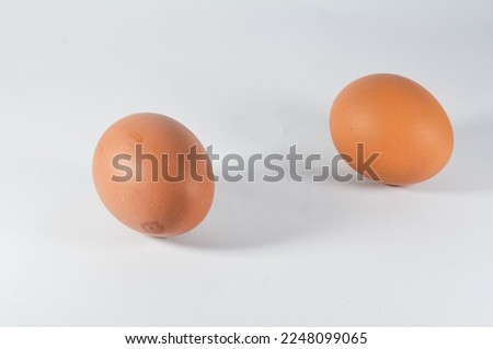 Two raw chicken eggs isolated on a white background.
