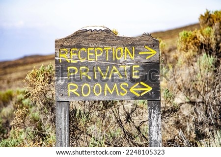 Wooden sign Reception and Private rooms near the road. 