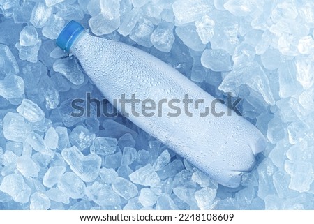 Cold bottle of water over ice cubes. Food and drink background.