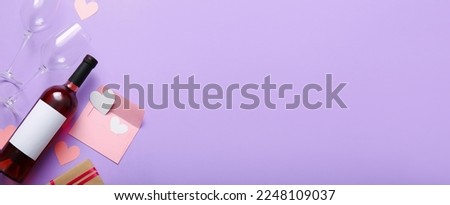 Composition with bottle of wine, glasses, envelope and paper hearts on lilac background with space for text. Valentines Day celebration
