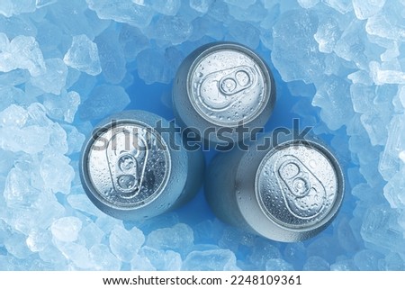 Cold silver cans of beer in ice cubes, top view. Food and drink background.