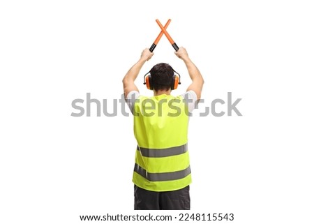 Rear view shot of an marshaller signalling with crossed wands isolated on white background Royalty-Free Stock Photo #2248115543
